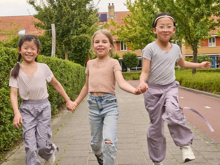 3 meisjes lopen hand in hand op de stoep